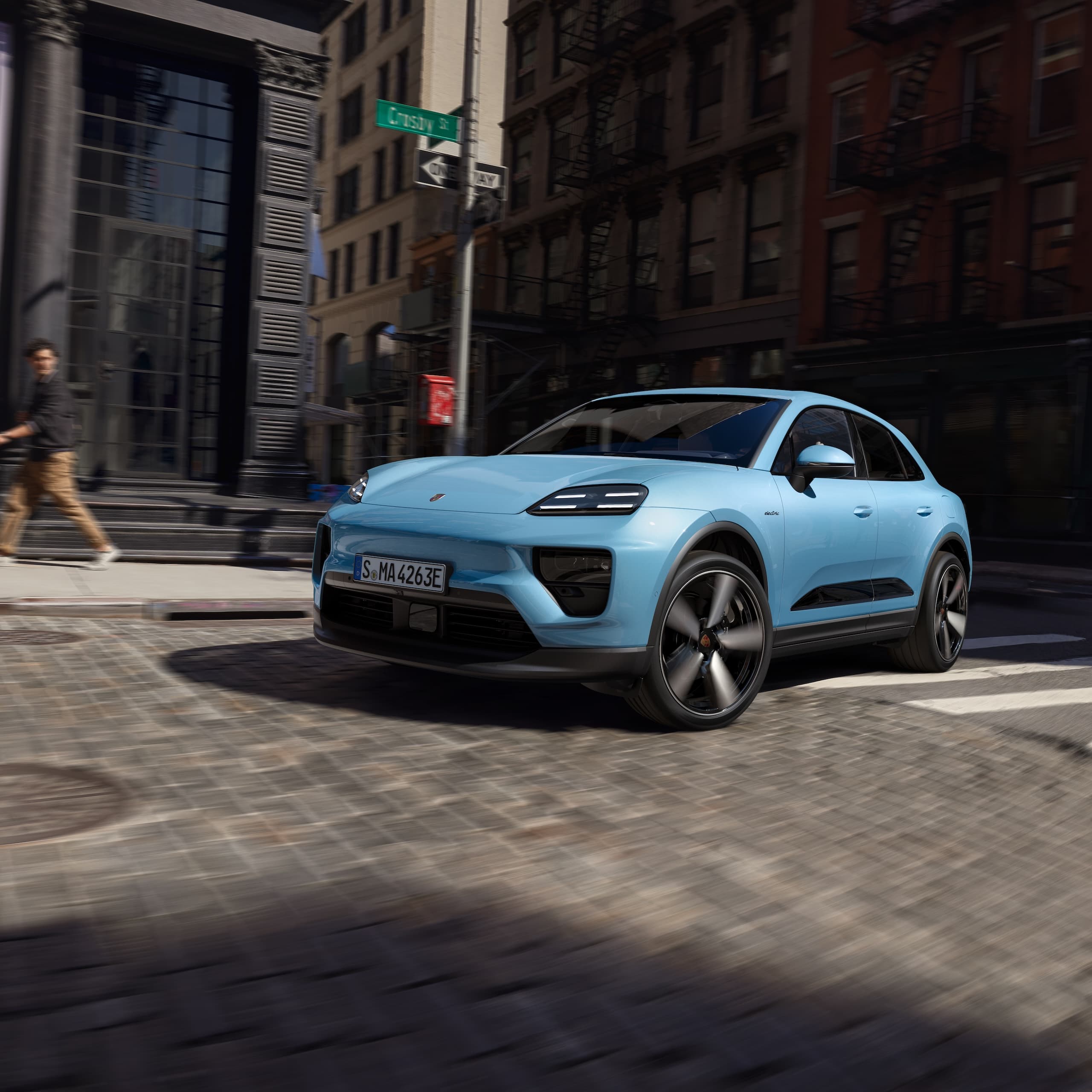 Ein Porsche vollelektrischer Macan, der in einem urbanen Szenario eine Strasse hinunterfährt.