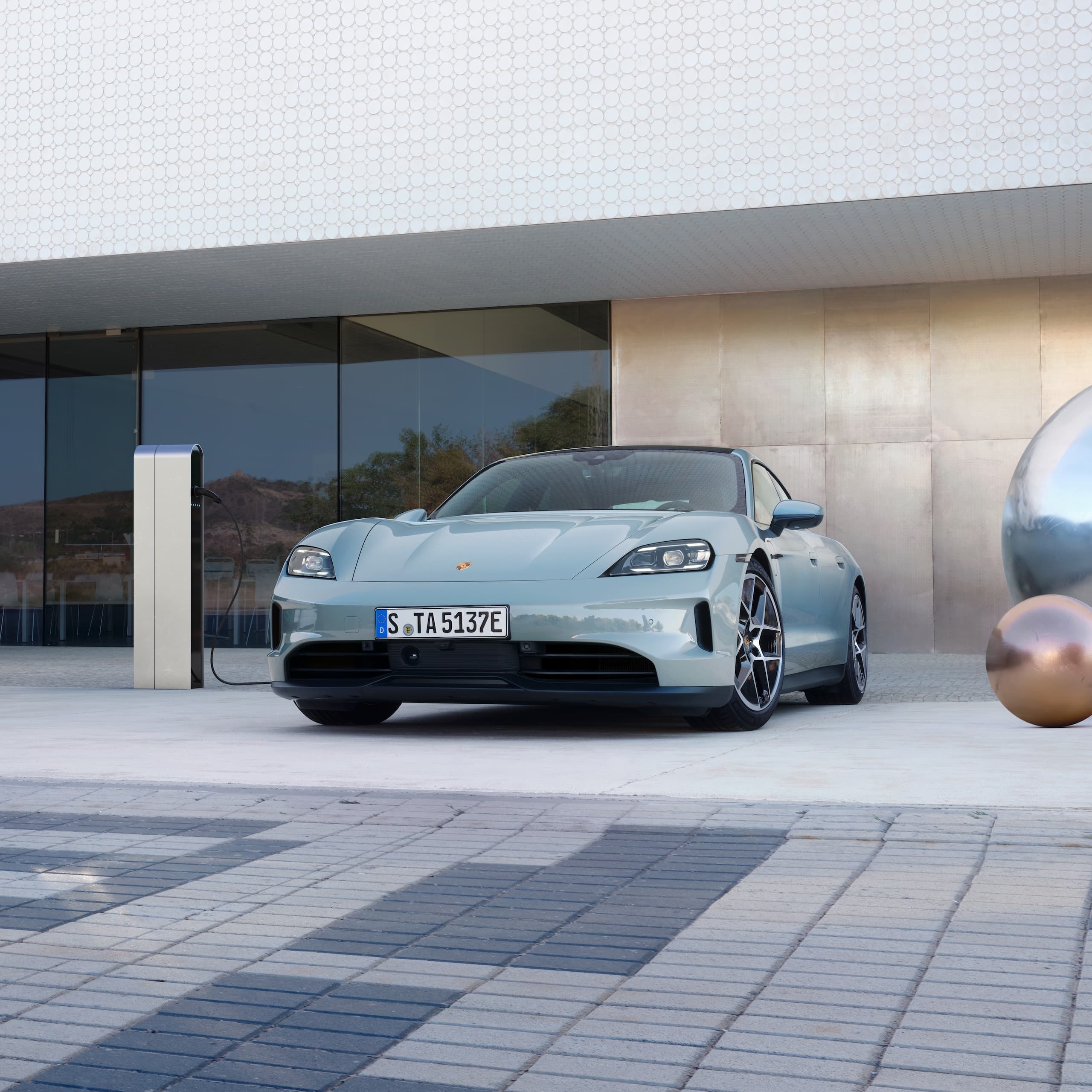 Ein Porsche Taycan parkte draussen vor einem modernen Gebäude.